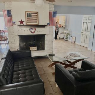 A cozy living room with a fireplace, decorated with flag-themed ornaments and black couches.