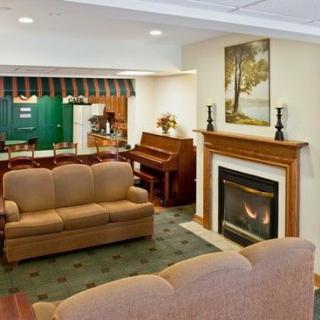 A cozy living room featuring a fireplace, sofa, and piano.