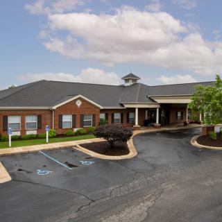 A single-story brick building with a parking lot and accessible parking spaces under a cloudy sky.