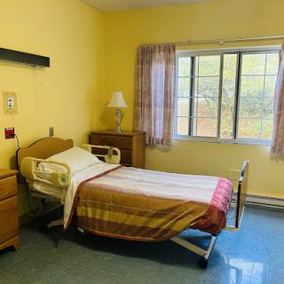 A hospital room featuring a patient bed and warm yellow walls, designed for comfort and care.