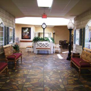 A spacious lobby with benches, a central clock, and decorative plants.