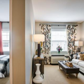 A modern apartment showcasing a cozy living room and adjacent bedroom with stylish decor and furnishings.
