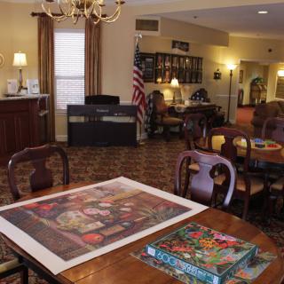 A cozy room with wooden furniture, featuring a table with a partially completed puzzle and an American flag in the background.