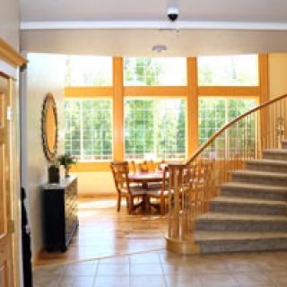 A bright and spacious interior featuring a curved staircase, large windows, and a cozy dining area with wooden furniture.