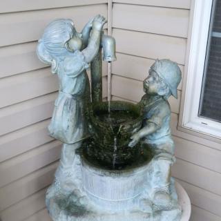 A decorative statue fountain depicting two children at a well.