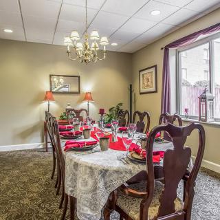 An elegant dining room with a long table set for a meal, featuring a chandelier and decorative elements.