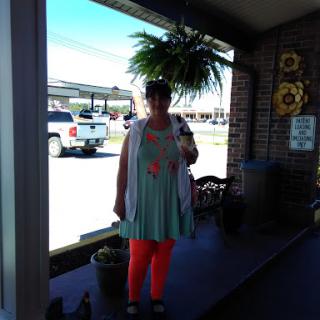 A person standing outdoors with a vibrant outfit and a hanging plant.