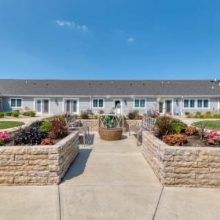 A picturesque garden pathway leading to a charming single-story building with colorful flower beds.