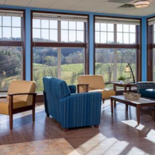 A spacious living room with large windows offering a scenic view, featuring comfortable seating and natural lighting.