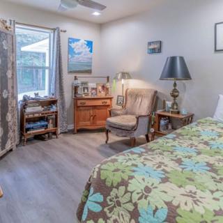 A cozy bedroom with a floral bedspread, a comfortable chair, and various decorations.