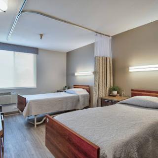 A clean and well-lit hospital room with two beds, designed for patient comfort.