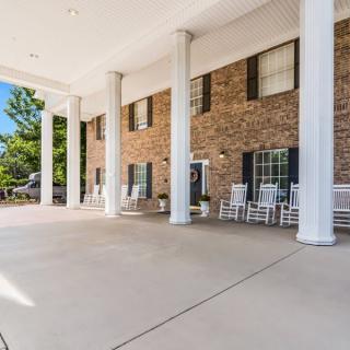 The entrance of a building with large columns and rocking chairs.