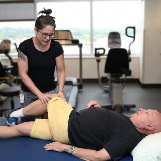 A therapist assists a patient with leg exercises during a physical therapy session.
