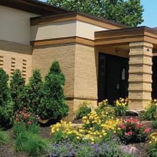 A modern building with a vibrant garden in front.