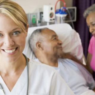 A nurse smiling while attending to a patient in a hospital setting.