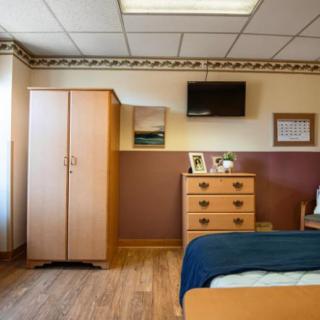 A cozy bedroom with wood furniture, including a dresser and wardrobe, and a mounted television.