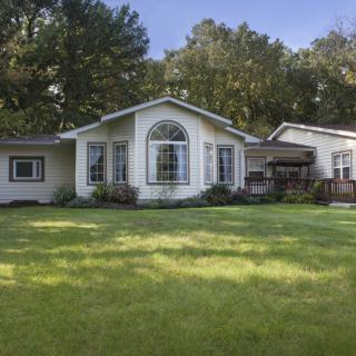 A charming residential house with a well-maintained lawn surrounded by trees.
