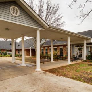 A building with a covered entrance featuring columns and a driveway.
