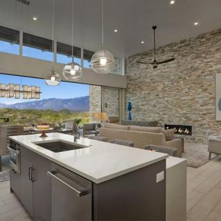 A modern open-plan kitchen and living room with large windows offering a stunning mountain view.