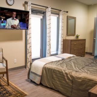 A cozy bedroom with a television, neatly made bed, and stylish furniture.