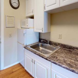 A small kitchen area with white cabinets, a marble-patterned countertop, and essential appliances.
