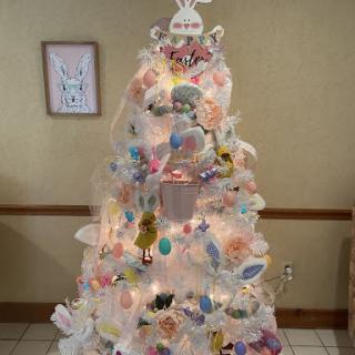 A beautifully decorated pastel-colored Christmas tree with an Easter theme, adorned with lights and unique ornaments.