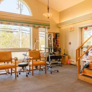 A well-lit physical therapy room with exercise equipment and seating.