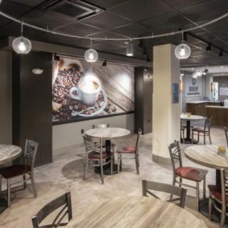 A cozy cafe interior with round tables, chairs, and artistic wall decor.