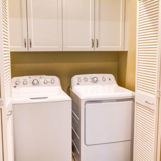 A compact laundry area featuring a washer and dryer set with overhead storage cabinets.