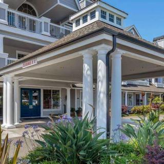 A well-maintained residential building entrance with columns and surrounding garden.