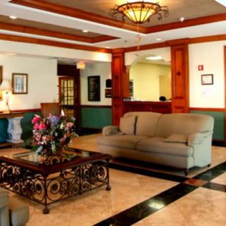 A well-furnished hotel lobby featuring a comfortable sofa, elegant table with floral arrangement, and sophisticated lighting.