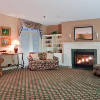A cozy living room featuring a fireplace, patterned carpet, and comfortable seating.