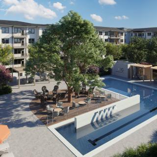 A modern apartment complex with a landscaped courtyard featuring a fountain and outdoor seating.