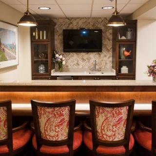 A cozy home bar setup with elegant chairs and ambient lighting.