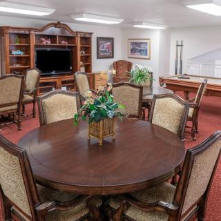 A cozy living area with a wooden dining table, chairs, a TV, and decorative elements.