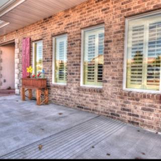 A welcoming exterior view of a house featuring a brick wall and elegantly designed windows.