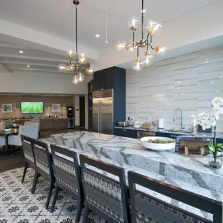 A modern kitchen with a large island counter and stylish chandeliers.