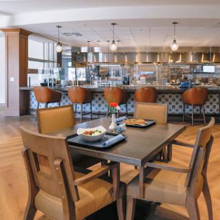 A modern dining area featuring a stylish kitchen, wooden chairs, and a well-set table.
