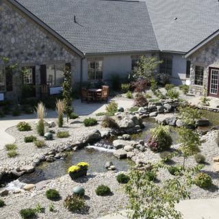 A beautifully landscaped courtyard with a garden pond surrounded by stone buildings.