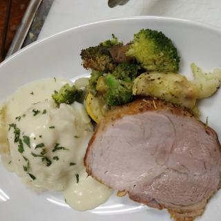 A delicious plate featuring sliced pork, creamy mashed potatoes, and roasted broccoli.