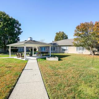 A cozy house with a spacious backyard featuring a covered patio and a well-maintained lawn.