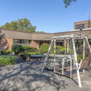 A serene outdoor space featuring a swing set surrounded by well-maintained landscaping and a clear blue sky.