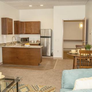 A modern open-plan kitchen and living area with wooden cabinets and stainless steel appliances.