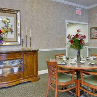 A well-decorated dining room featuring a wooden table set with chairs and floral arrangements.