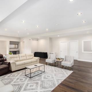 A spacious and modern living room featuring comfortable seating, a patterned rug, and bright overhead lighting.