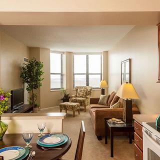 A cozy and modern apartment living room with a dining area, featuring comfortable furniture and large windows.