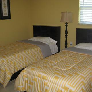 A cozy bedroom with twin beds and a lamp by the window.