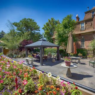 A charming garden patio with a gazebo, surrounded by colorful flowers and greenery.