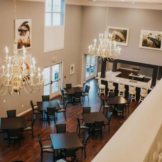 An elegant restaurant interior with chandeliers, a bar area, and neatly arranged tables and chairs.