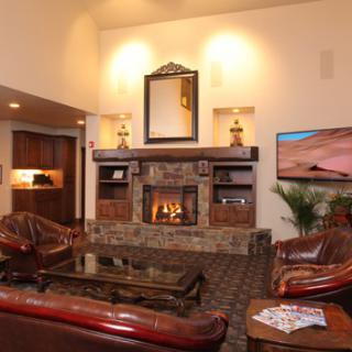 A cozy living room with a stone fireplace, leather sofas, and warm lighting.
